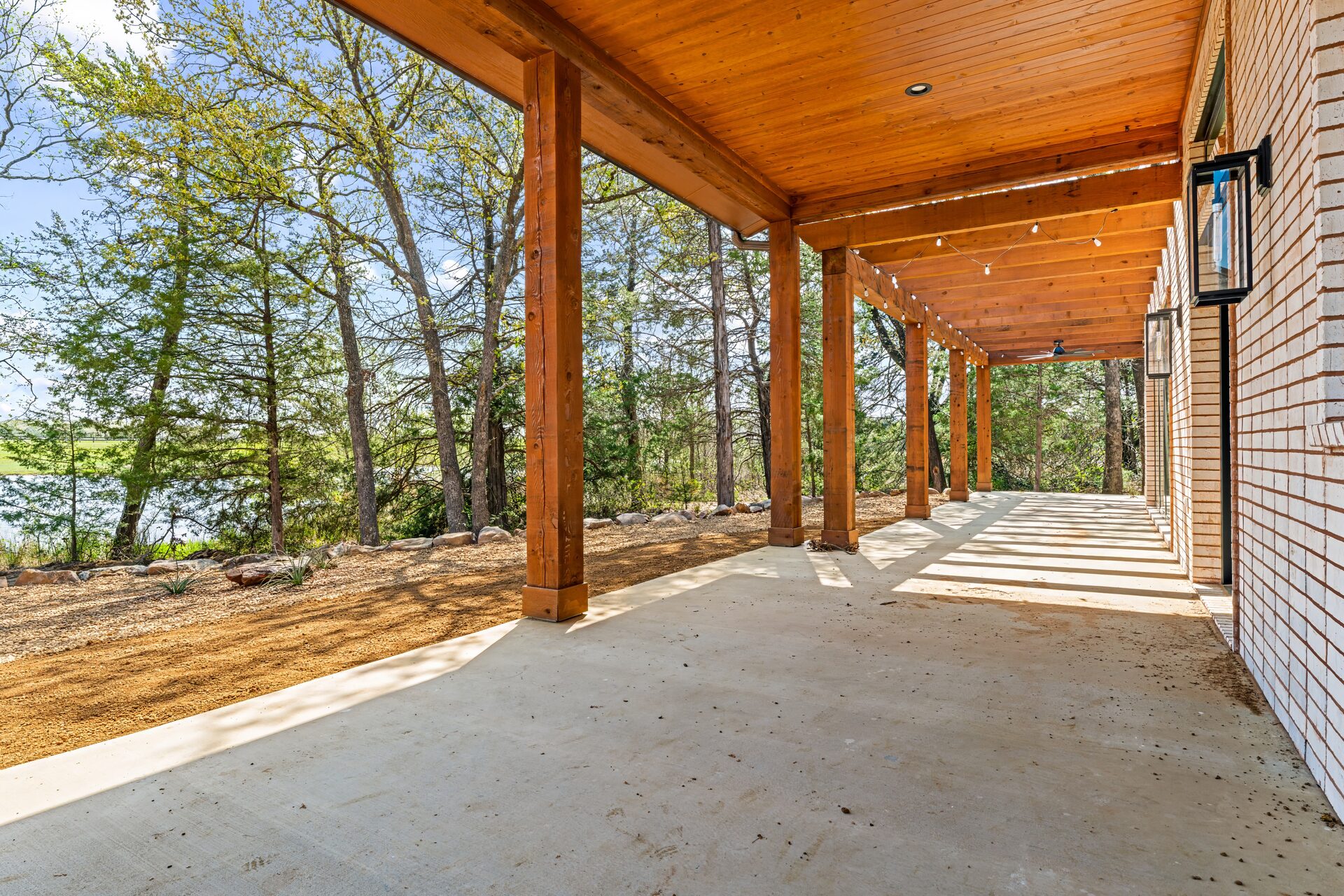 Ironwood custom home covered back porch with wood beam ceiling and lake view by RBCS Inc in North Texas