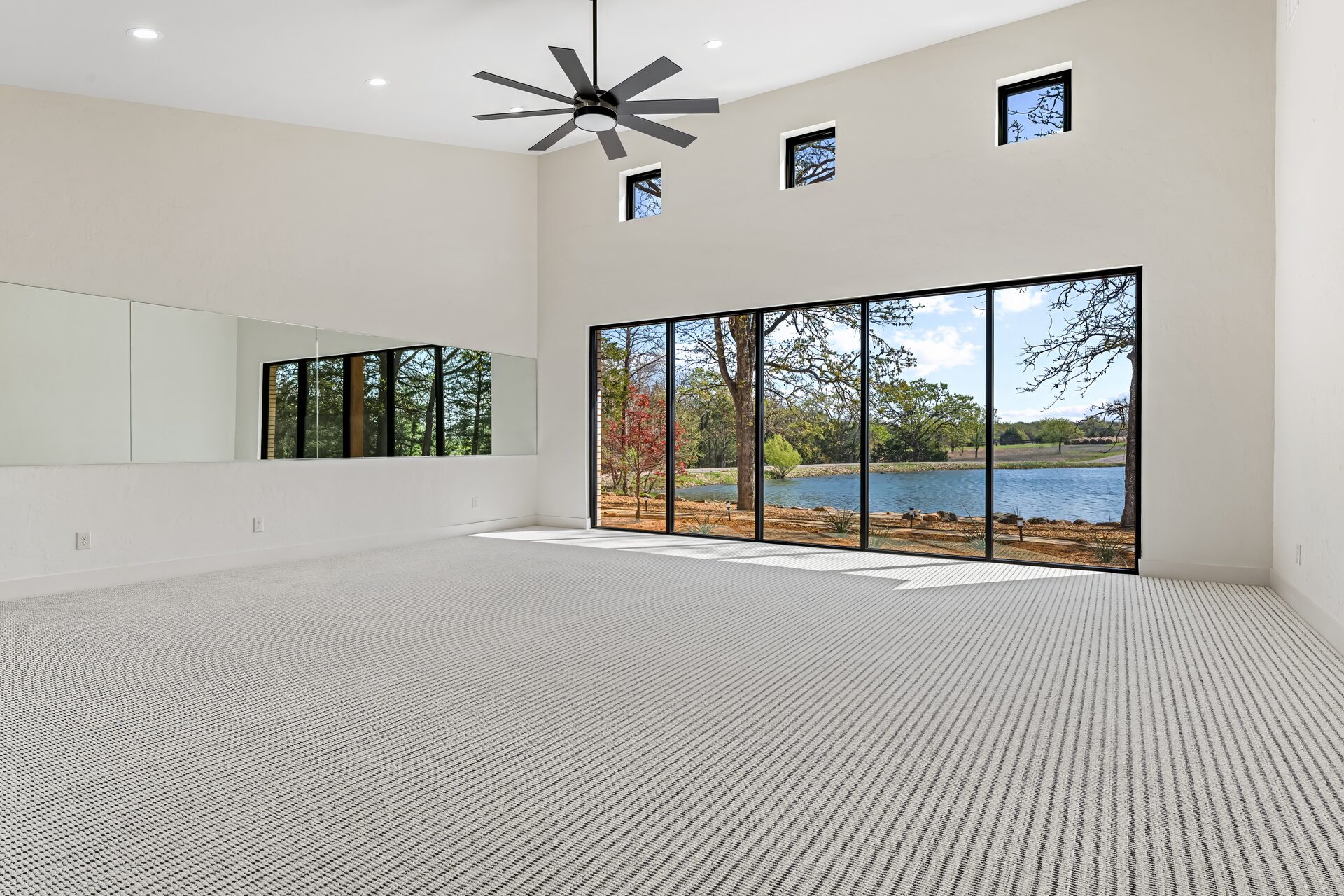 Ironwood custom home exercise room with lake view and floor-to-ceiling windows by RBCS Inc in North Texas