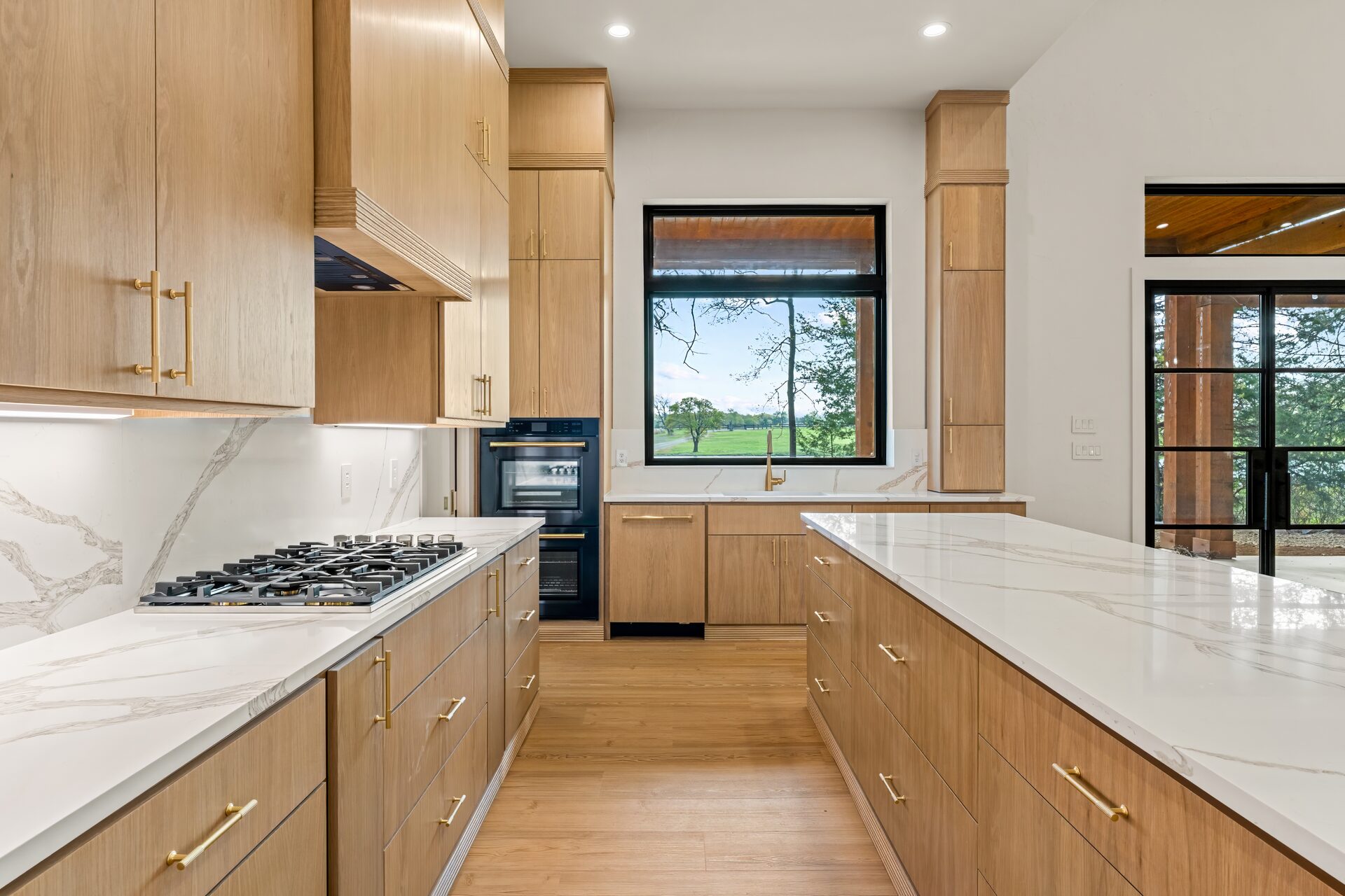 Ironwood custom home kitchen with gas cooktop, marble countertops, and wooded view by RBCS Inc in North Texas