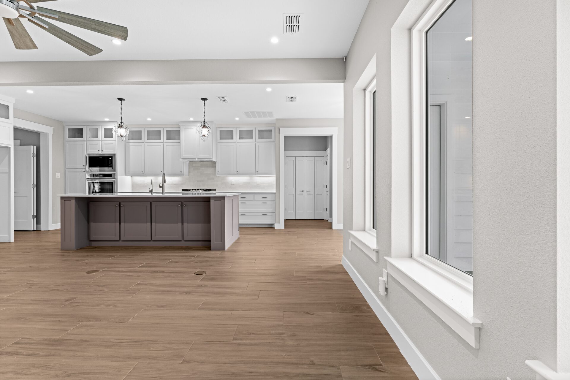 Post Oak custom home kitchen island with double sink and crystal chandelier by RBCS Inc in North Texas